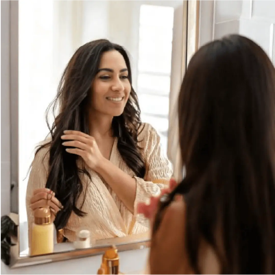 Mujer sonriendo mientras utiliza productos de cuidado personal.